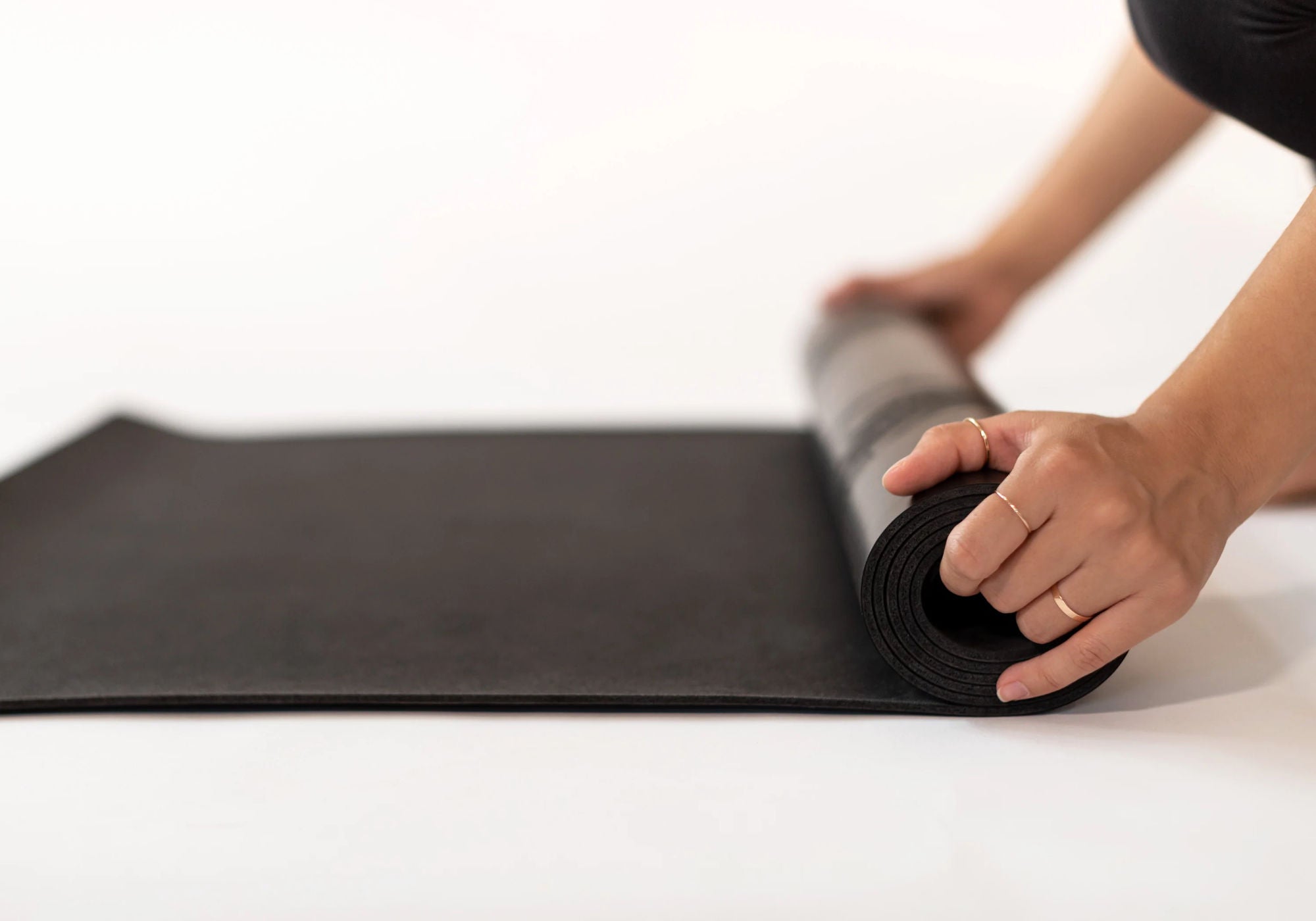 A woman rolling up a Lumi Eco Wolf Yoga Mat