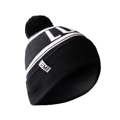 LUMI Cold Bundle black knit bobble hat with white striped pattern and LUMI logo, featuring a pom-pom on top, photographed against white background, ideal for cold weather activities