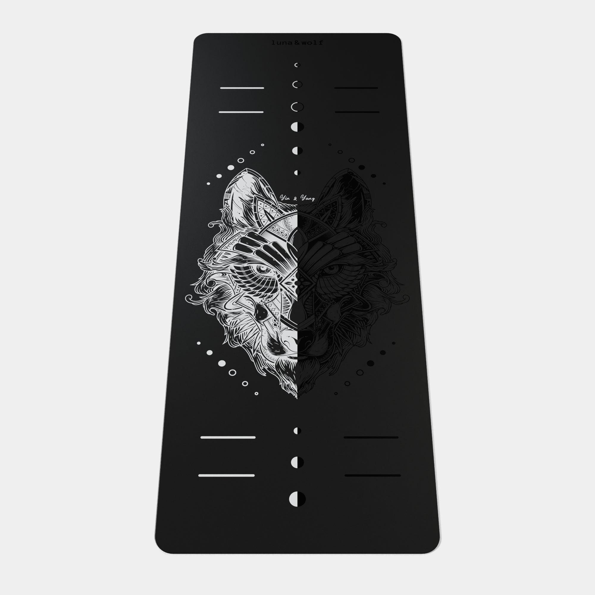 Eco Wolf Yoga Mat - YinYang features a striking black mat with white alignment markers and a split wolf design - half detailed illustration, half minimalist silhouette - creating a balanced yin-yang effect. Moon phase symbols line the center, with positioning guides at both ends.