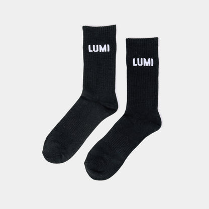 LUMI Pro Bamboo Socks in classic black with white LUMI logo branding, displayed as a pair on light background, featuring ribbed texture and elasticated cuffs for athletic performance and comfort