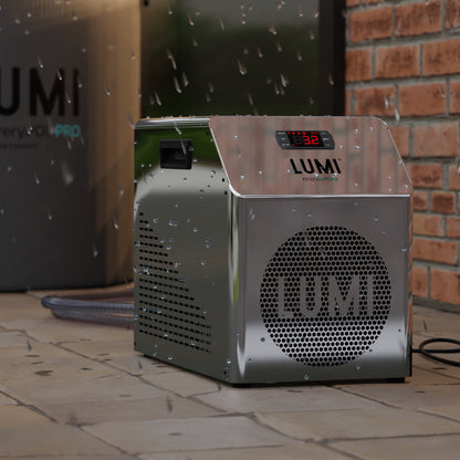 LUMI miniULTRA Chiller unit with sleek mirror-finish metal exterior, digital temperature display, and perforated circular brand logo, photographed outdoors on stone tiles with water droplets visible, showcasing its IPX6 water-resistant design.